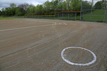 The on deck circle of an unoccupied baseball field on a cloudy day..