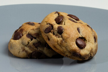 Two cookies with chocolate chips on a gray background