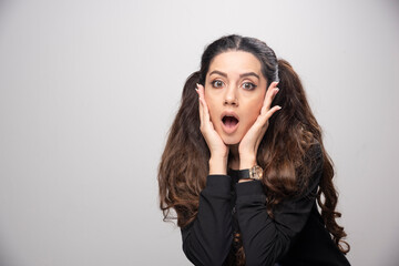 Surprised girl in printed sweatshirt standing on gray background