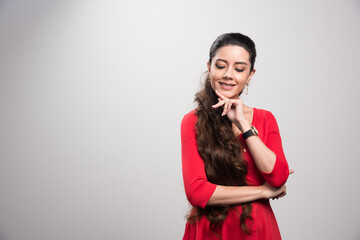 Feeling free and happy. Attractive young woman in red dress looking away and smiling while standing against grey background