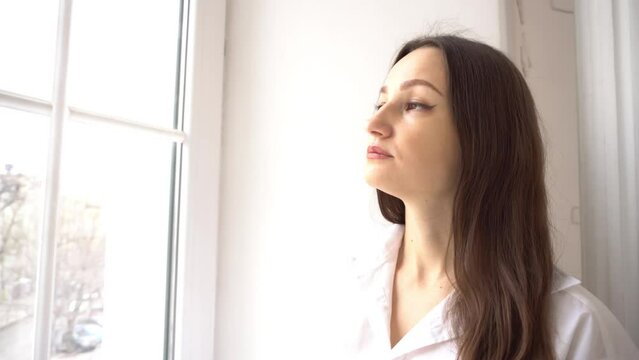 4k Young woman is looking out the window