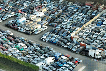 Aerial view of big parking lot of junkyard with rows of discarded broken cars. Recycling of old...