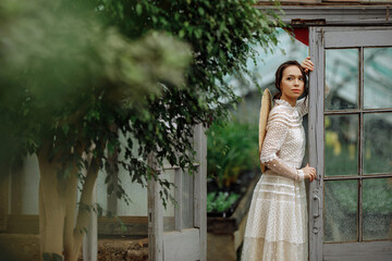A young girl in a vintage dress in a tropical greenhouse.