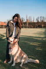 Obraz premium latin mature woman standing outdoors smiling with a retriever dog at sunset portrait