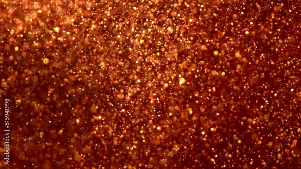 Sticker slowly falling golden particles in red fluid. gold dust particles and bokeh move slowly in red liqui