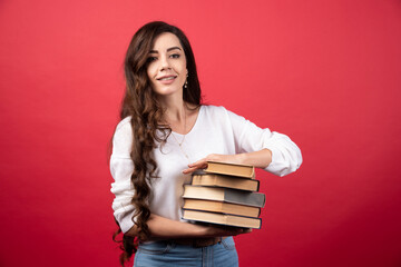 Pretty woman carrying books on a red background