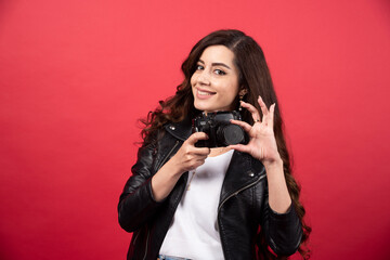 Beautiful woman photographer holding photo camera on a red background