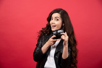 Obraz premium Beautiful woman photographer holding photo camera on a red background