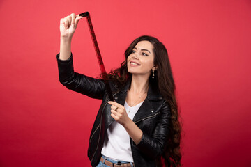 Young woman looking on a photo tape on a red background