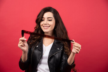 Young woman looking on a photo tape on a red background