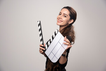 A filmmaker girl holding an open blank clapper board and looking positive