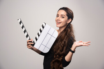 A filmmaker girl holding an open blank clapper board and looking positive