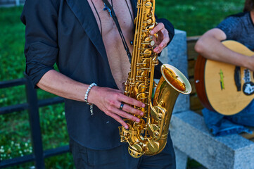 Fototapeta premium A street musician plays the saxophone. Duo saxophone and acoustic guitar. Street concert