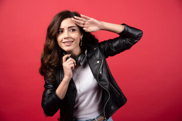 Young woman taking off headphones and posing on a red background