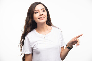 Fototapeta premium Attractive woman in white shirt pointing at somewhere