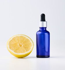 Blue glass bottle with pipette, next to it is half a lemon on a white front.