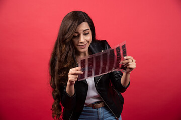 Young woman looking on a file with a photo tape on a red background