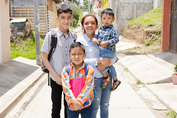 Young mother with her happy children ready for her to go to school-Hispanic family outside her...