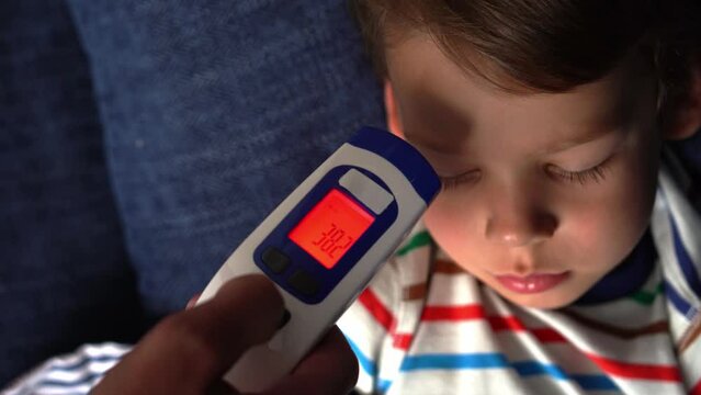 Portrait of sick ill little preschool child boy. Measuring body Hight temperature. Taking medicine curing syrup antipyretic from spoon. Children illness, disease, parent care. electronic thermometer
