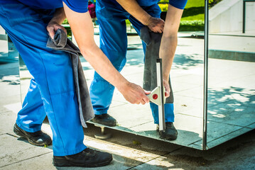 an employee of a cleaning company washes a glass scraper mirror. cleaning the park on a summer day....