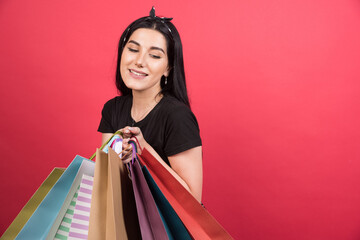 Young woman looking on her bags on red background