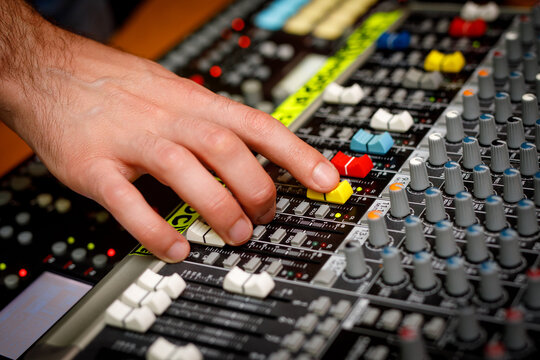 Hand of a sound engineer on sound console mixer. Equalizer control