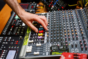 Hand of a sound engineer on sound console mixer. Equalizer control