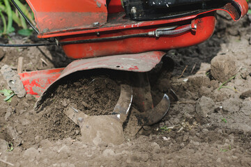 Red moto plow plows the ground. Mechanization of heavy manual labor in the cultivation of the land....