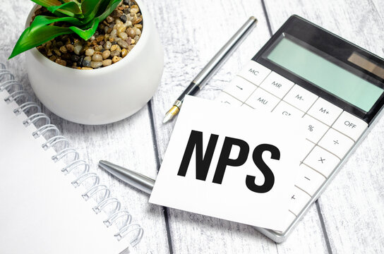 Text NPS on paper card and calculator on wooden background