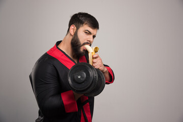 Fototapeta na wymiar Young man eating a banana and holding a dumbbell