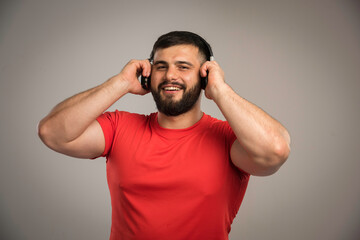 Fototapeta na wymiar Male dj in red shirt wearing headphones and listening to music