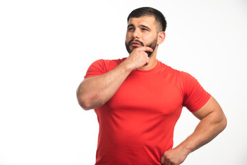 Sportive man in red shirt demonstrating his arm muscles and looks confident