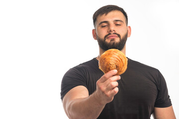 Sportive man in black shirt showing doughnut and his indifference - obrazy, fototapety, plakaty