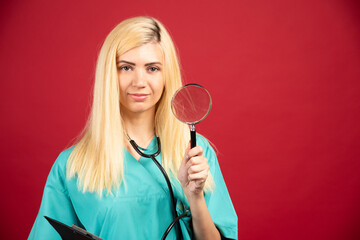 Portrait of beautiful nurse posing with magnifying glass