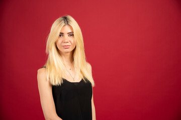 Fototapeta premium Portrait of blonde woman standing on red background