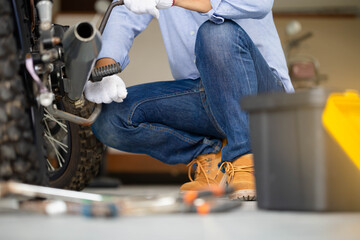 Mechanic fixing motorbike in workshop garage, Man repairing motorcycle in repair shop, Repairing and maintenance concepts