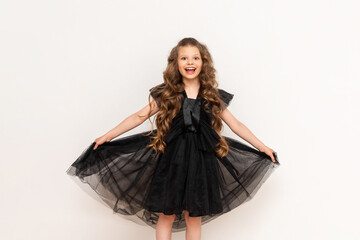 A charming little girl with curly hair and a fluffy dress on a white isolated background. A beautiful princess on Black Friday.