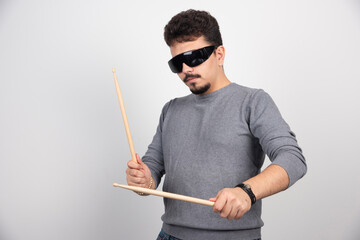 A drummer in black sunglasses holding drum sticks and looks very energic