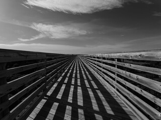 Black and white image of a wooden bridge with shadows