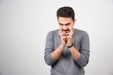 Sly man in gray t-shirt against white background