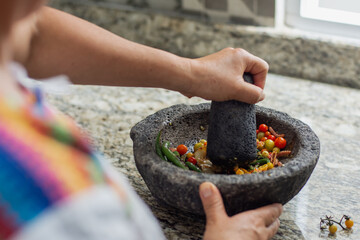 Unrecognizable woman preparing a traditional mexican sauce in a molcajete