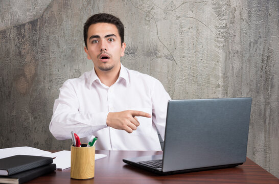 Businessman pointing at laptop and sitting at the desk