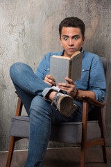 Young man reading a book and sitting on chair