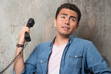 Naklejka premium Photo of young man talking on phone and sitting on chair
