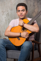 Young musician hugging the guitar on marble background