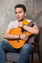 Young musician hugging the guitar on marble background