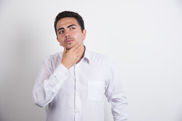 Young businessman holding his chin on white background