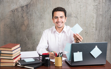 Office employee happily showing his memo pad at the office desk