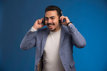 Male dj in grey suit wearing headphones and relaxing