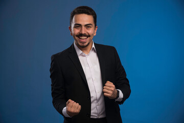 Businessman in black suit makes luck sign